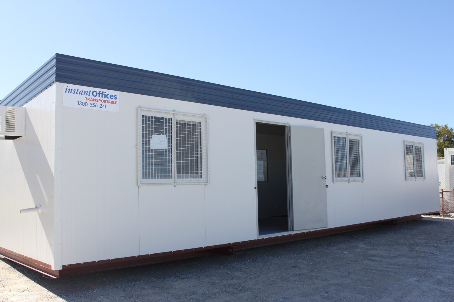 Portable modular office building by Instant Offices featuring white walls, security windows, and a blue roof.
