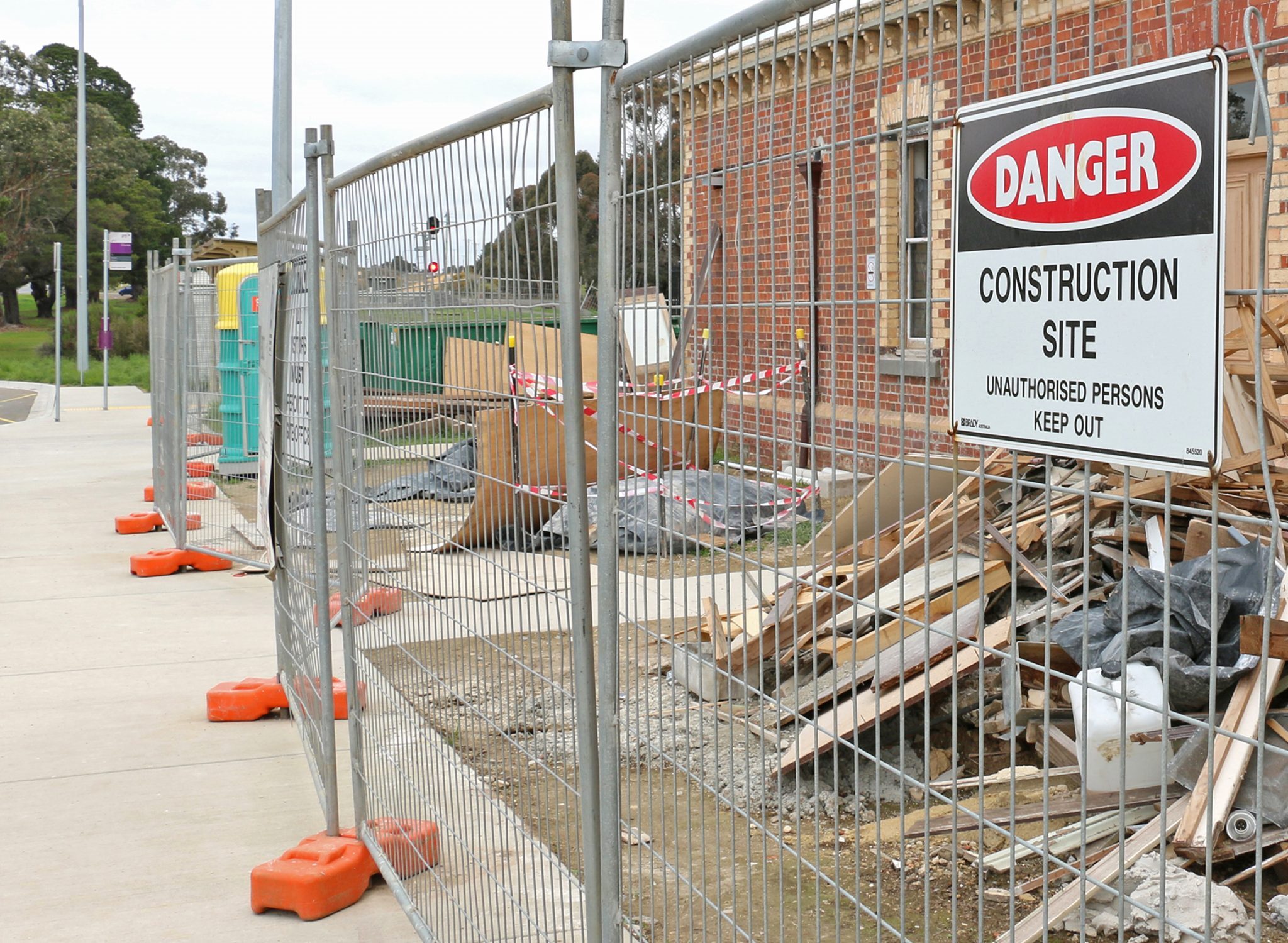 Construction site secured with metal fencing and a 'Danger Construction Site' sign warning unauthorized persons to keep out.