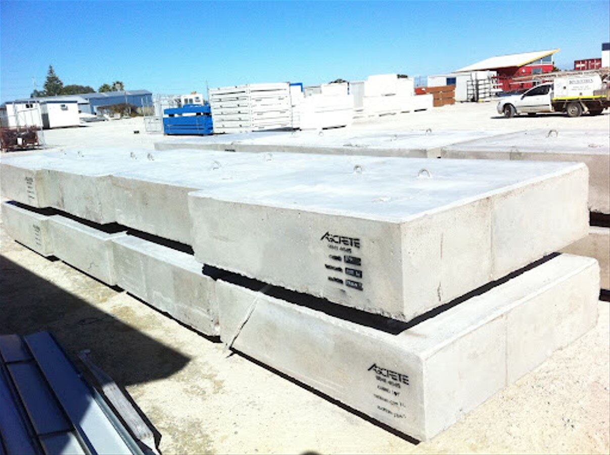 Stack of precast concrete blocks used for construction, stored in an outdoor industrial yard under bright sunlight.
