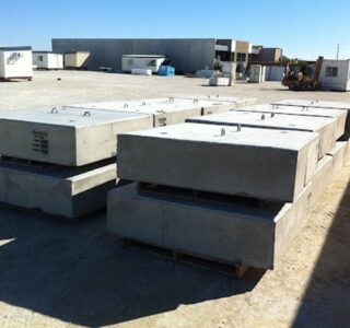 Stacks of precast concrete footings on pallets at a construction storage yard.