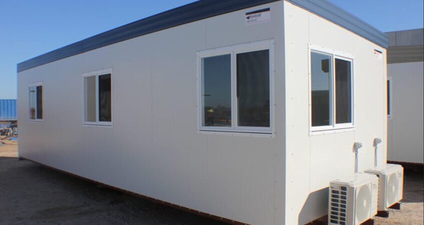 White portable office building with multiple windows and external air conditioning units.