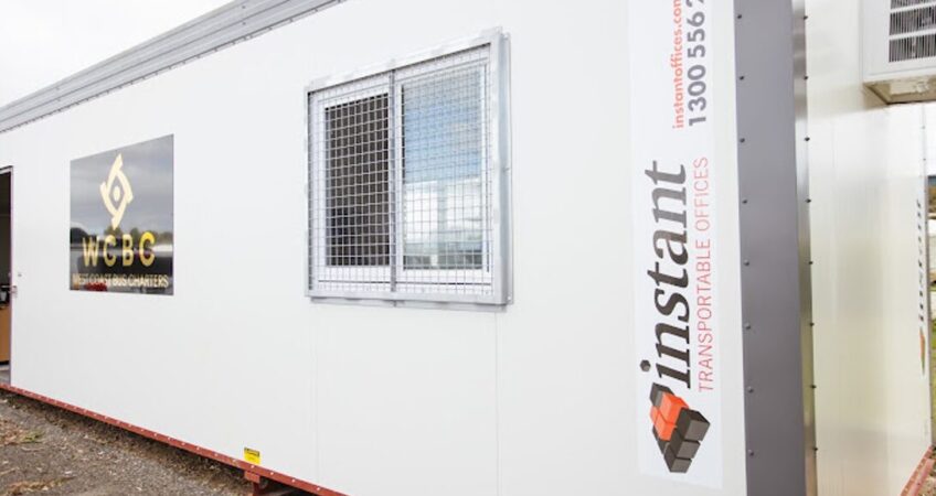White portable office container by Instant Office, featuring a security window and company logos on the side