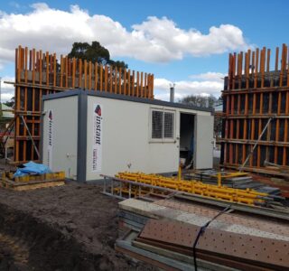 Demountable building unit at a construction site surrounded by building materials