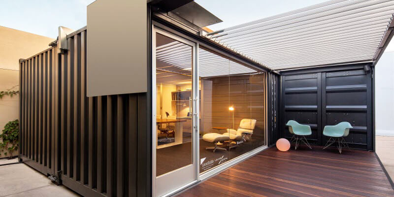 shipping container conversions with glass doors and outdoor seating area.