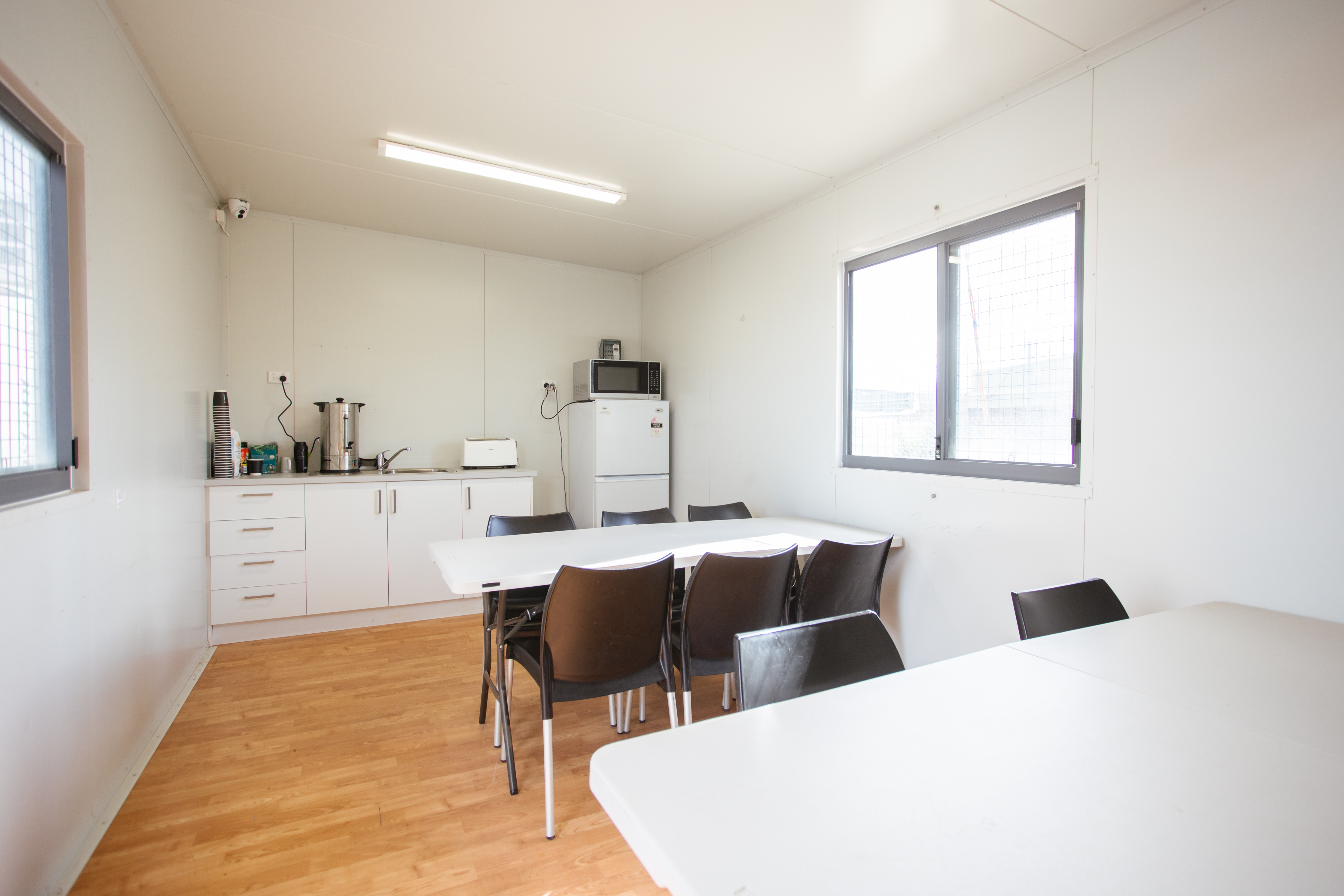 Interior fit-out of a portable crib room, featuring a kitchenette with sink, storage drawers, hot water system, and kitchen appliances