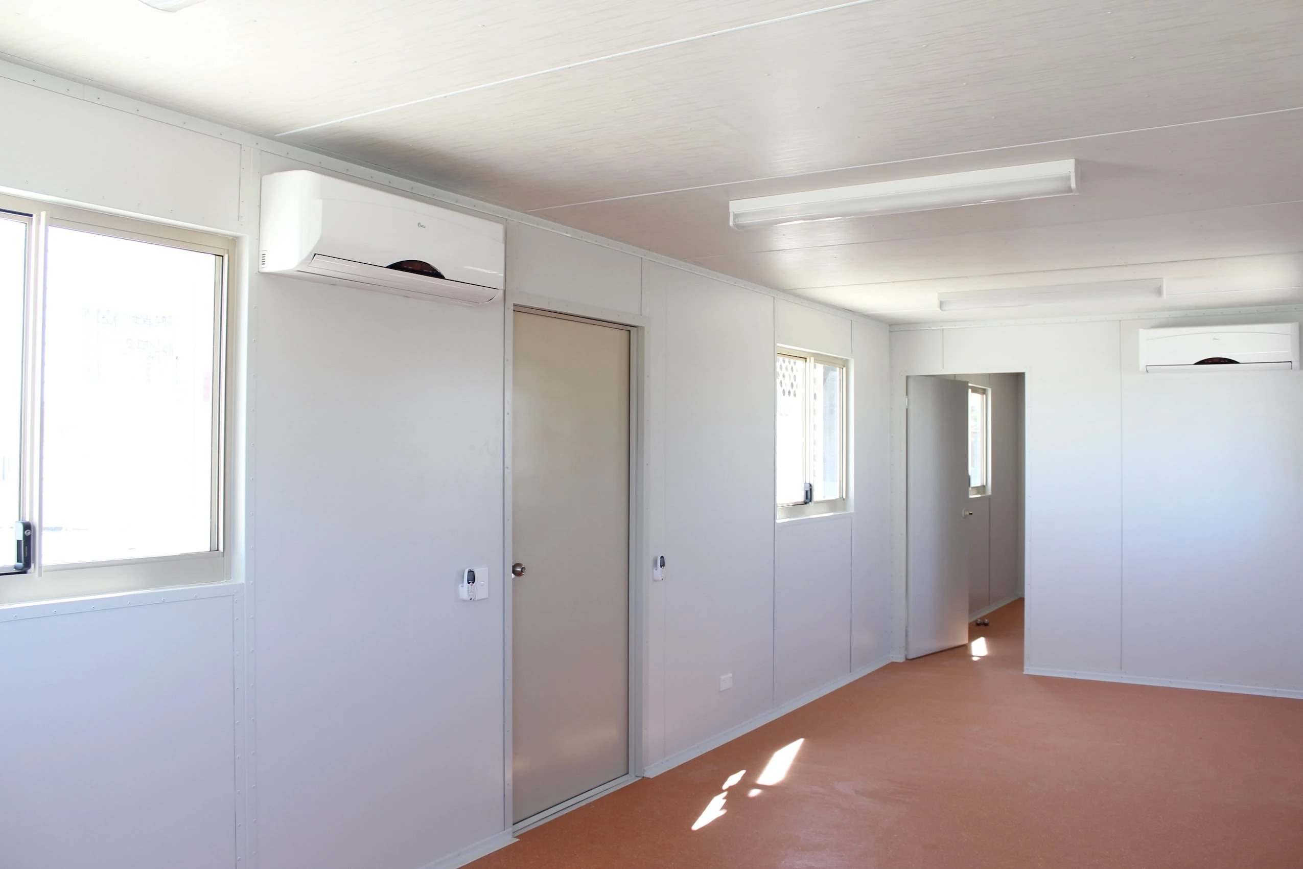 Interior of a two-room donga showing split system air con, windows, lighting, and partition walls