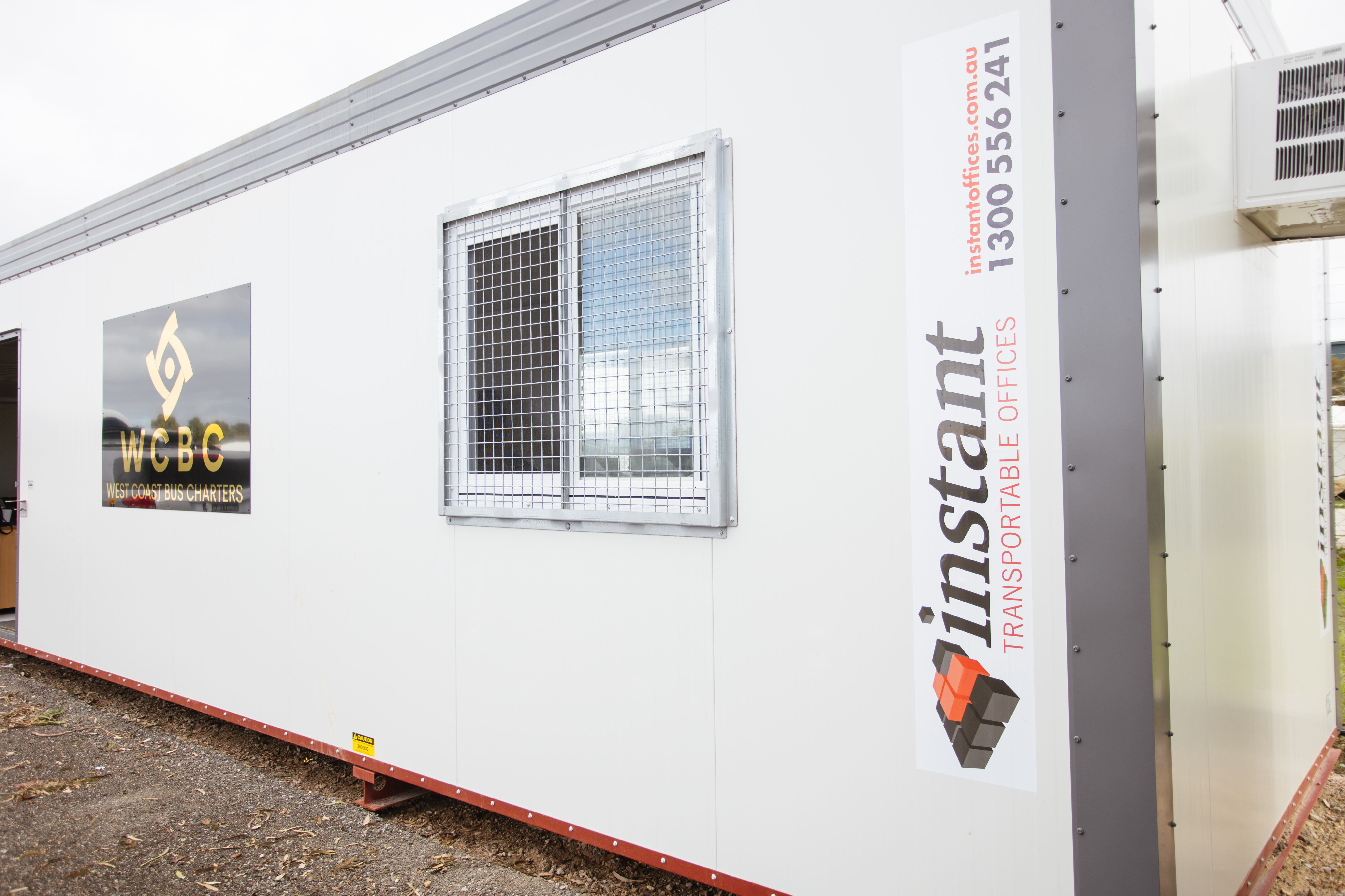 Portable site office by Instant Transportable Offices, featuring secure mesh window grills, air conditioning unit, and branded signage