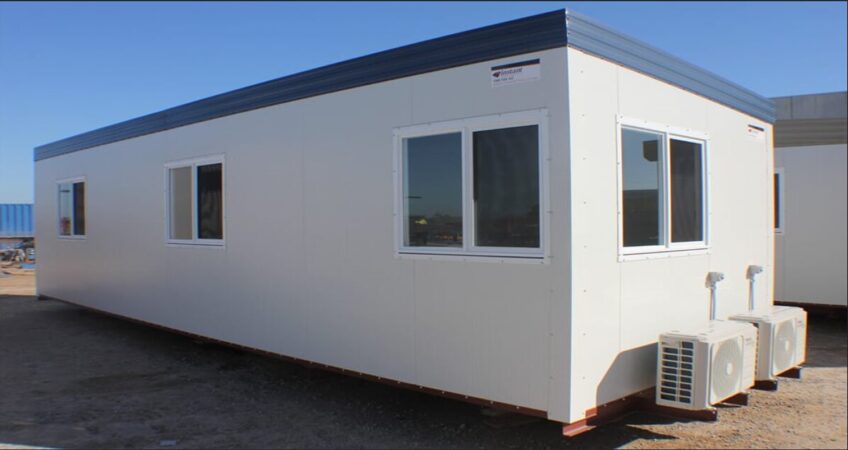 White portable office building with multiple windows and external air conditioning units.